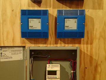 Tekmar zone controllers and PLC (programmable logic controller) relay for customized operation of 2 air to water heat pumps.