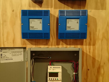 Tekmar zone controllers and PLC (programmable logic controller) relay for customized operation of 2 air to water heat pumps.