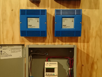Tekmar zone controllers and PLC (programmable logic controller) relay for customized operation of 2 air to water heat pumps.